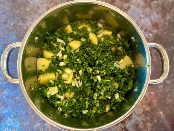 chopped potatoes, onion and kale in a pan with water