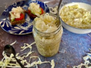 Is sauerkraut vegan friendly? Jar of homemade sauerkraut with toast in the background