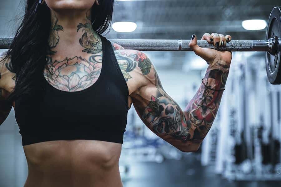 Does OMAD cause muscle loss? Image of the left arm of a female weightlifter covered in tattoes