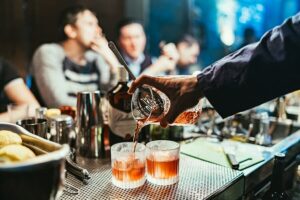 Hand pouring two drinks: is it worth it to give up alcohol?