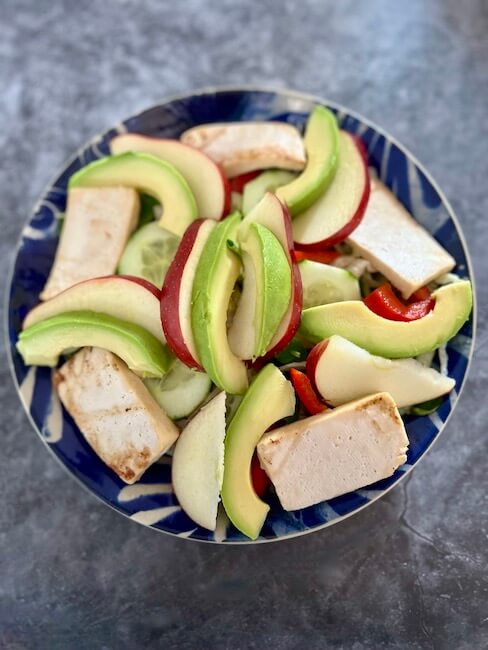Tofu salad bowl with sliced avocado and apple added