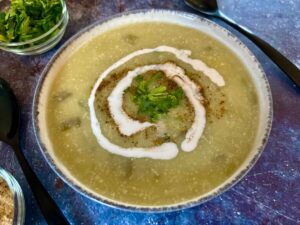Bowl of creamy vegan leek and potato soup with a swirl of vegan cream on top