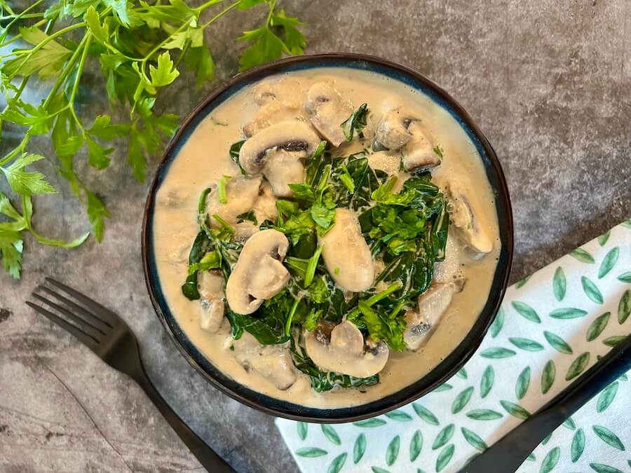 Bowl of vegan creamy garlic mushrooms with spinach and fresh parsley