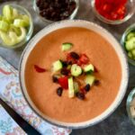 Bowl of authentic Spanish gazpacho with raisins and finely chopped pepper and cucumber on top
