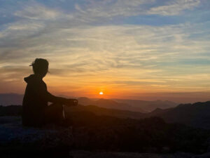 Silhouette of person meditating against sunset - article on symptoms before hypothyroidism