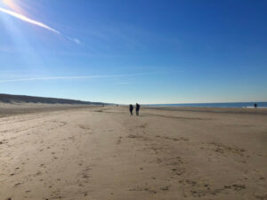 Strengthen your relationship - couple walking on a sandy beach with blue skies above